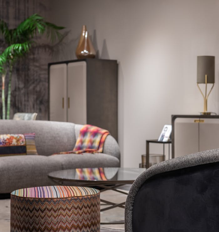 Soft sofas with colorful cushions placed near side table in modern living room with cupboards and decorations at home